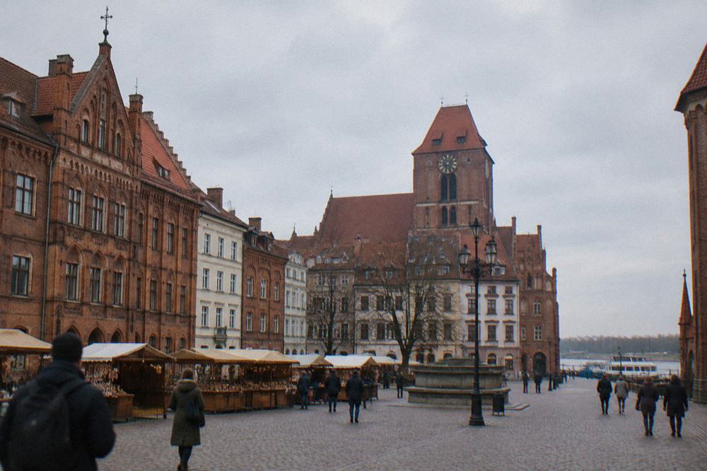 Gothic brick townhouses and a church tower above the rooftops of the Old Town of Toruń