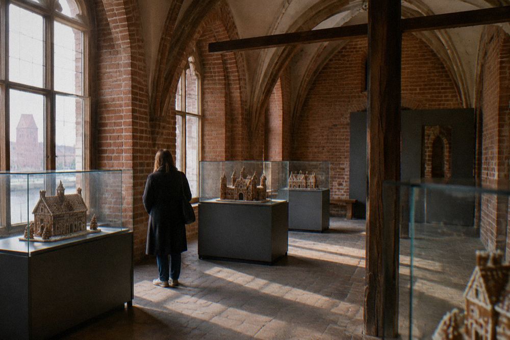 A historic gingerbread bakery interior with carved wooden moulds hanging on the wall and a stone hearth