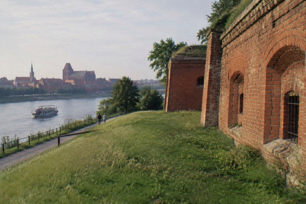 A brick wall of a nineteenth century fortress fort beside a grassy embankment