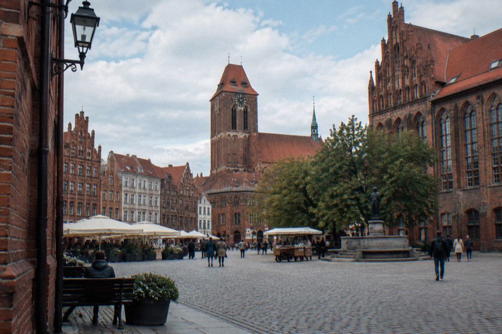 Gothic brick townhouses and a church tower above the old market square of Toruń