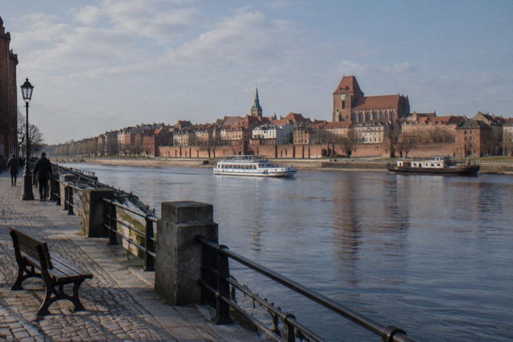 The Vistula river seen from the Toruń old town waterfront with brick buildings along the bank