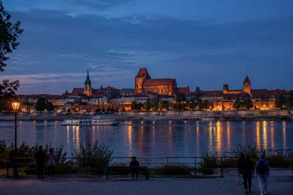 Panoramic view across the Vistula river of Toruń's old town rooftops and church towers at dusk