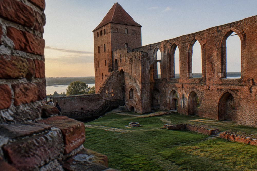 Red brick ruins of the Teutonic Castle in Toruń with grassy courtyard and arched walls