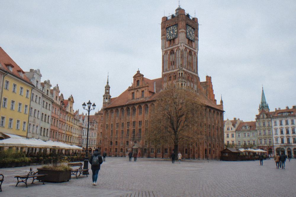 Red brick Gothic town hall rising above a wide market square lined with colourful merchant houses