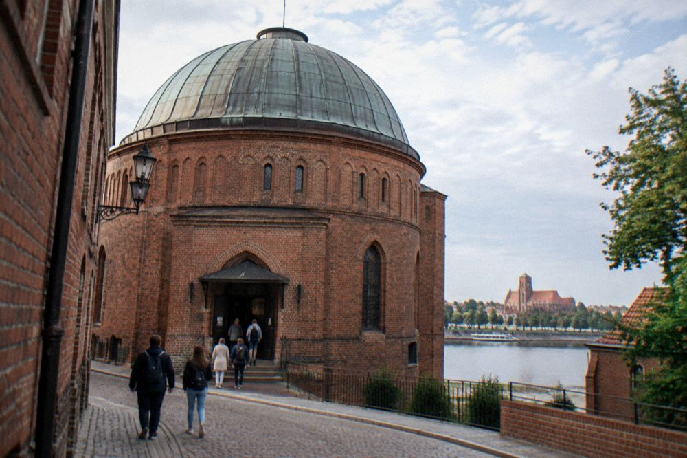 Planetarium dome building on a narrow brick street with visitors at the entrance