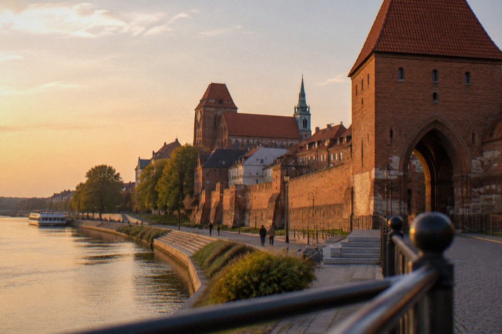 Riverside promenade along the Vistula with brick town walls rising above it