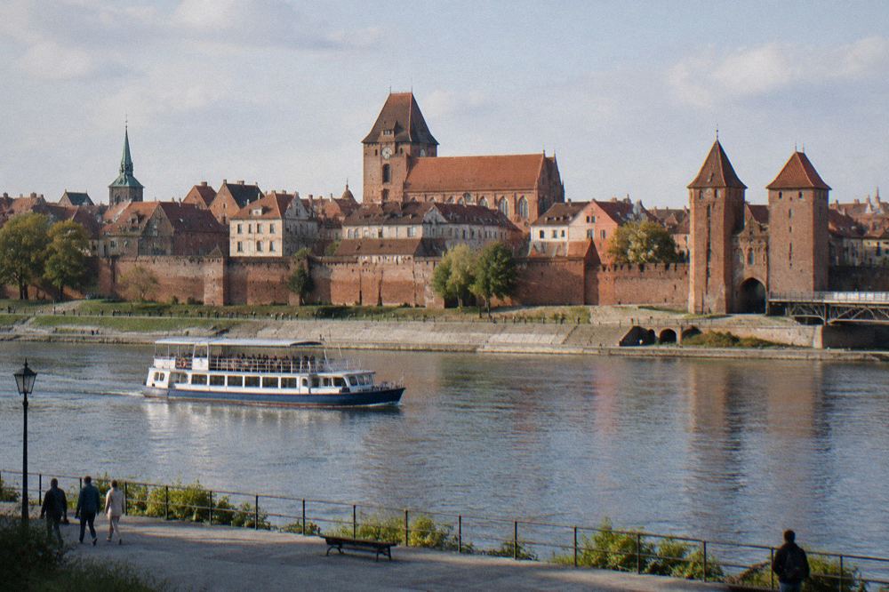 Boat on the Vistula with the brick walls and gates of Toruń behind it