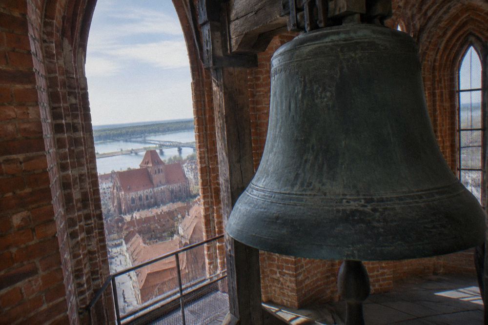 Large historic bell hanging inside a brick church tower