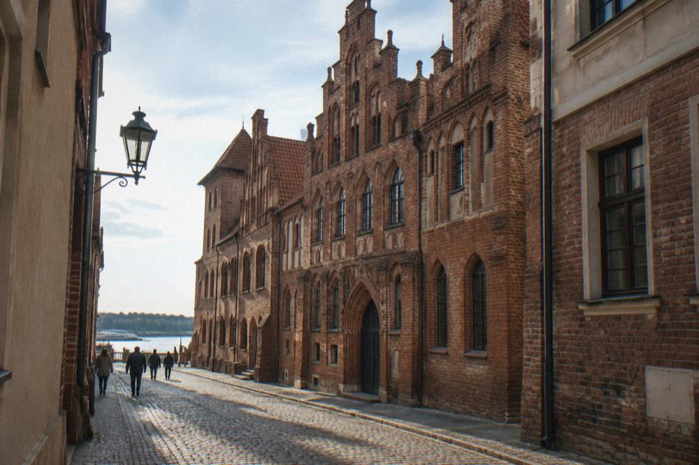 Gothic brick townhouses of the Copernicus House museum seen from a narrow street in Toruń's Old Town