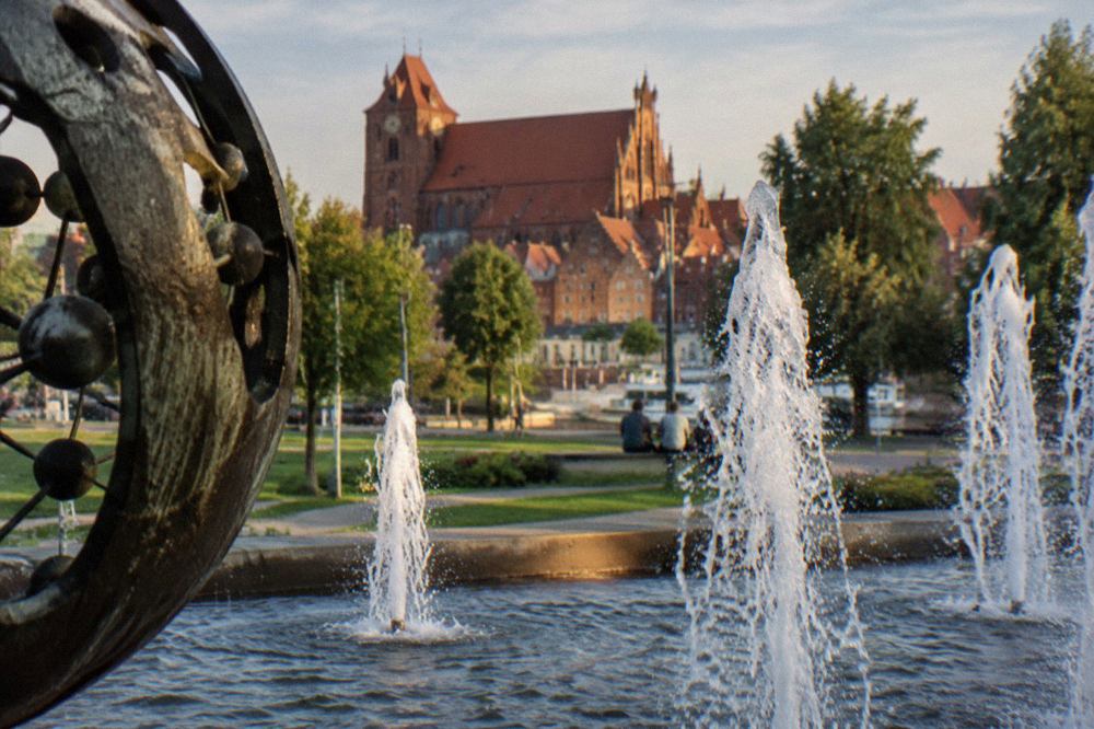 Jets of water rising from a fountain pool in a green park in Toruń