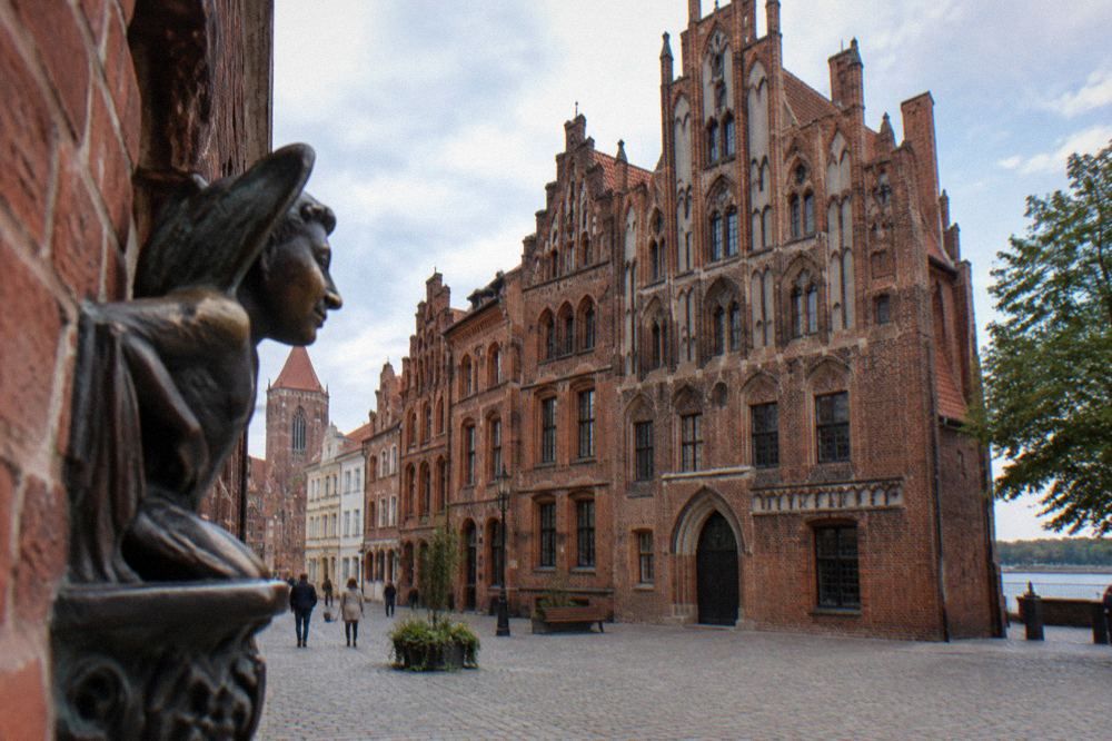 A cobbled square lined with Gothic brick townhouses in Toruń
