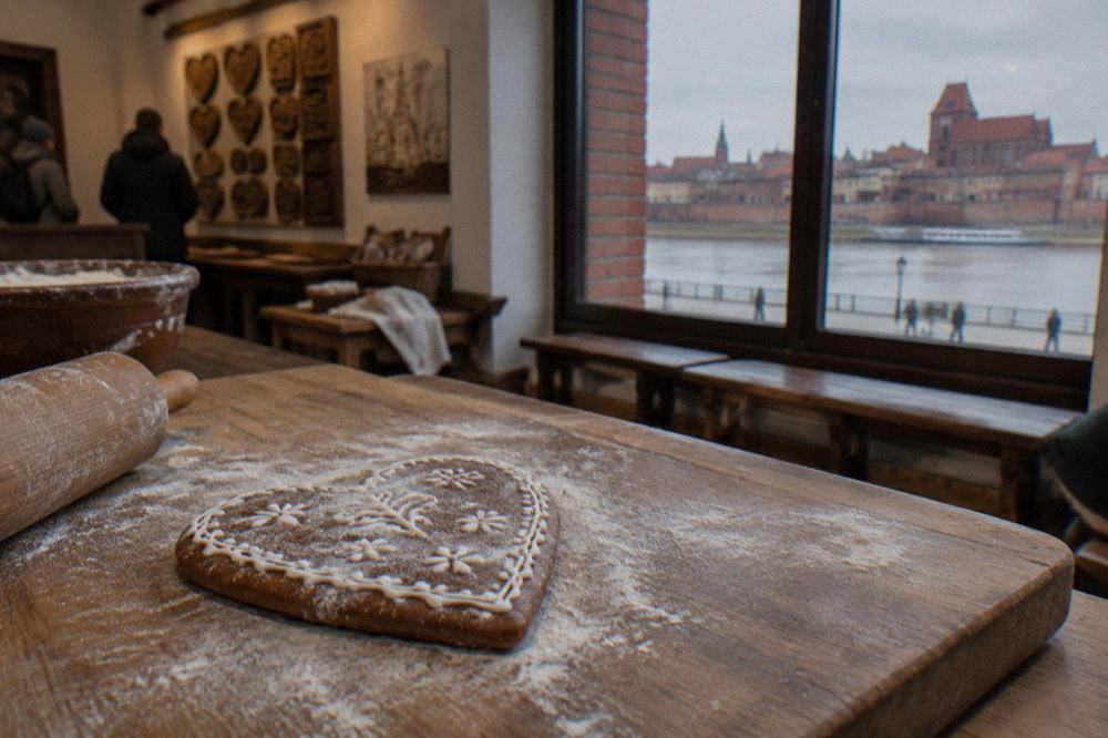 A finished gingerbread heart dusted with flour on a wooden board