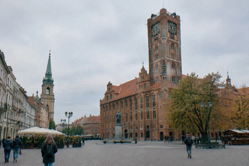 Red-brick Gothic town hall with a tall tower seen across the market square