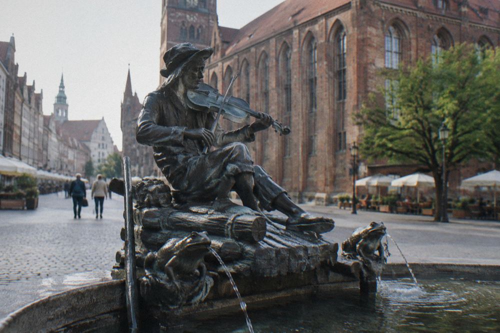 Fountain sculpture of a fiddling raftsman with frogs at the edge of the market square