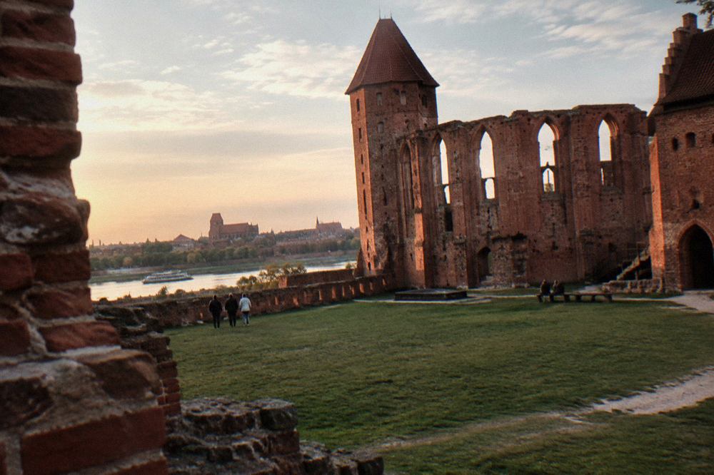 Red brick ruins of the Teutonic castle with a grassy courtyard in Toruń