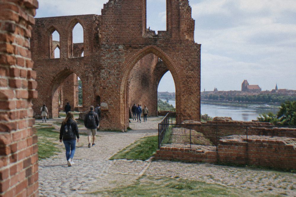 Visitors walking among the red brick arches of the castle ruins