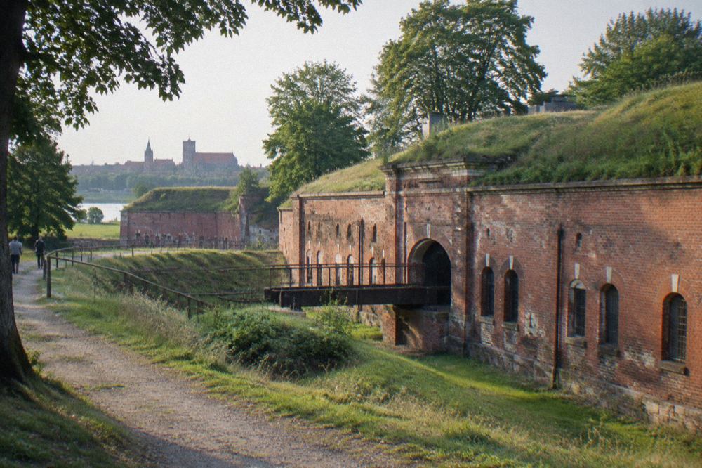 A brick nineteenth century fort with grassy ramparts and trees around it