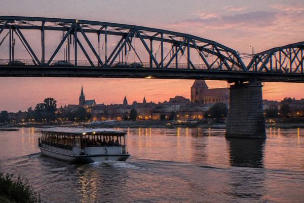 A wooden boat on the Vistula in the evening beside the Toruń skyline