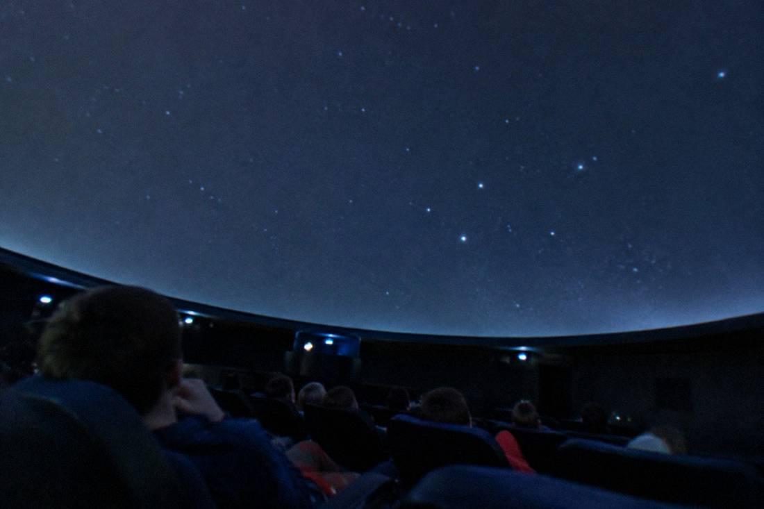 Reclined seats inside a dim planetarium dome in Toruń