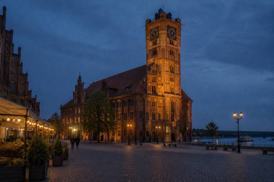 The brick Old Town Hall tower of Toruń against a dark blue sky