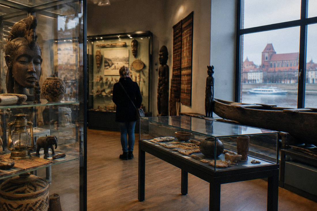A quiet museum gallery with glass cases of travel curiosities in Toruń's Old Town