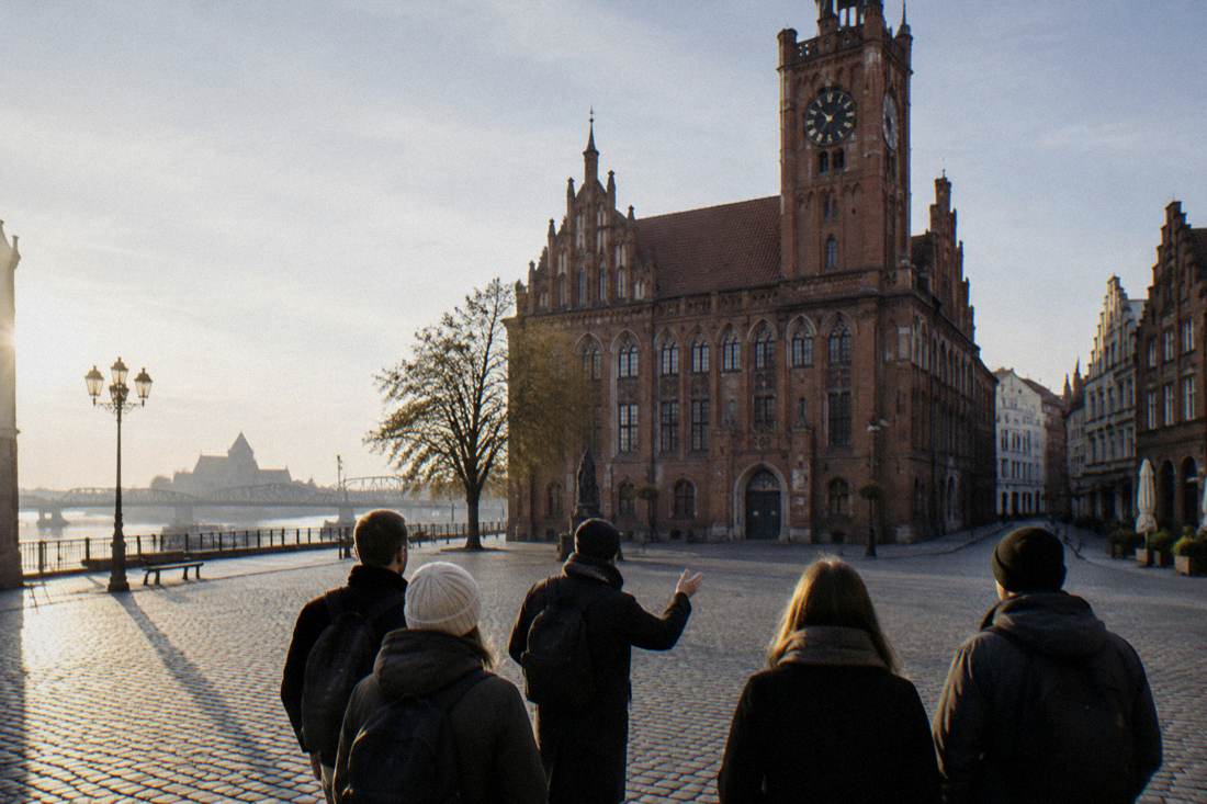 A guide and a small group in front of the Old Town Hall in Toruń at the start of the morning