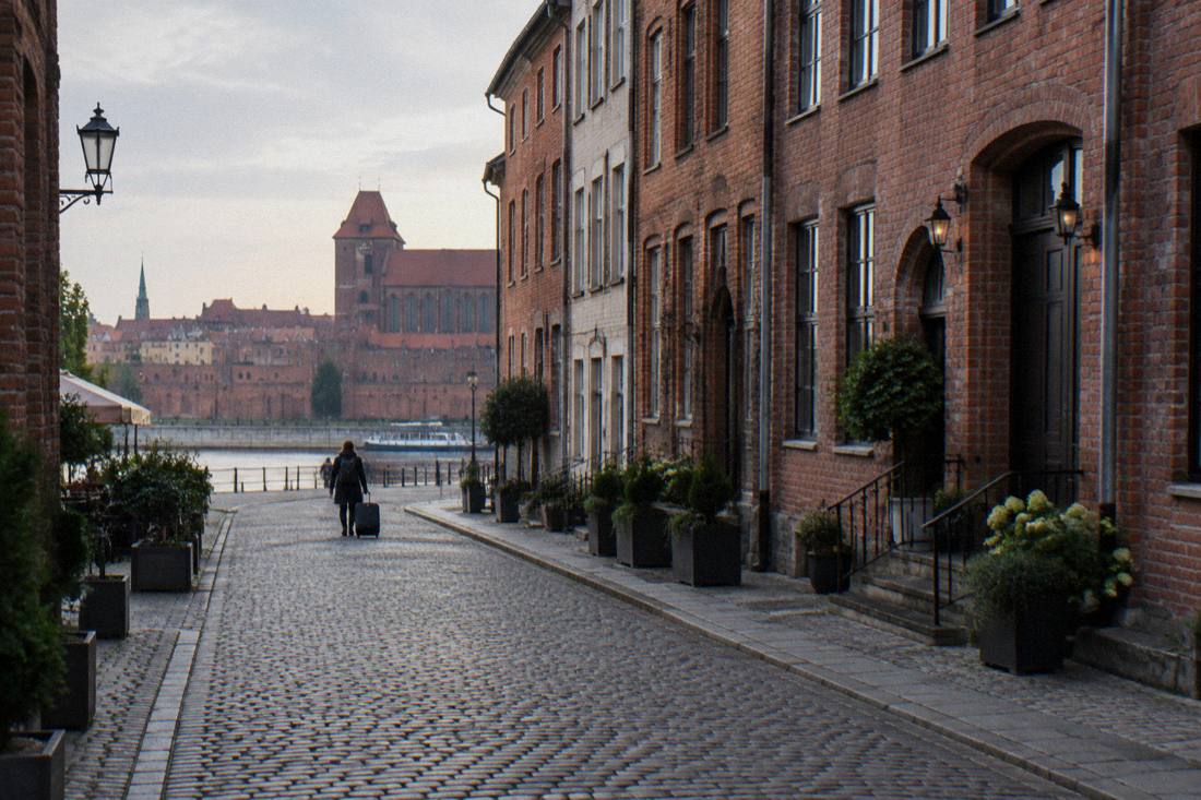 A narrow Old Town street in Toruń with brick townhouses and cobbles