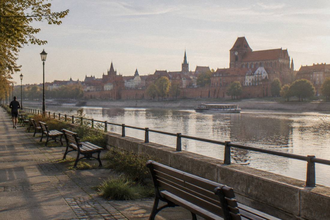 Benches on the Vistula embankment in Toruń with the brick walls behind