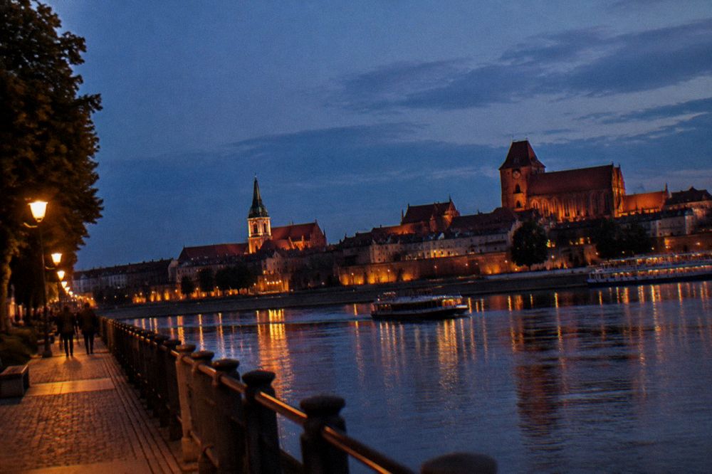 Evening light over the Old Town of Toruń with church towers and riverside buildings along the Vistula