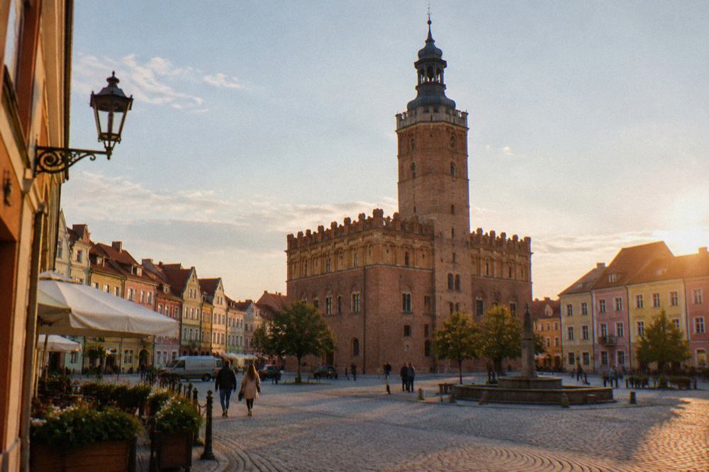 A Renaissance town hall with a tall tower standing above a market square lined with colourful townhouses