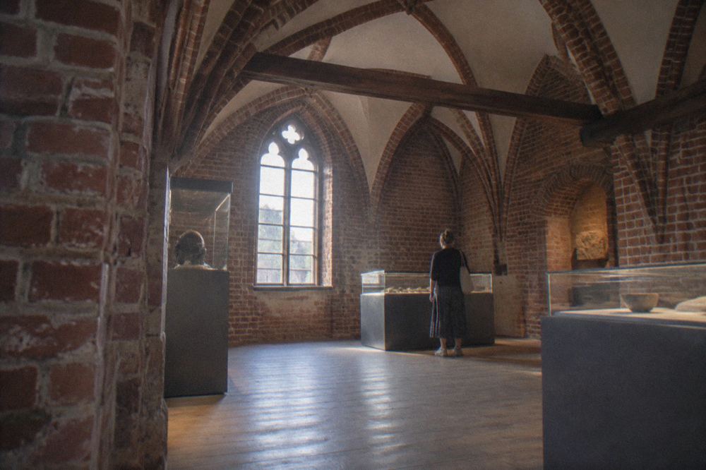 The interior of a regional museum with stone vaults and display cases of medieval artefacts