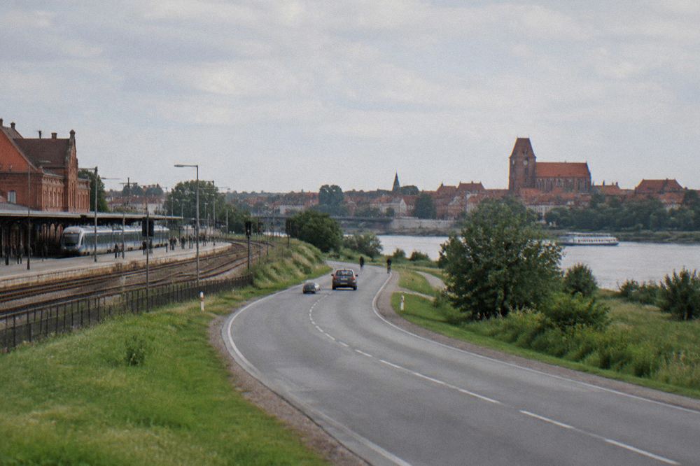 A road winding through green Polish countryside toward a distant church tower