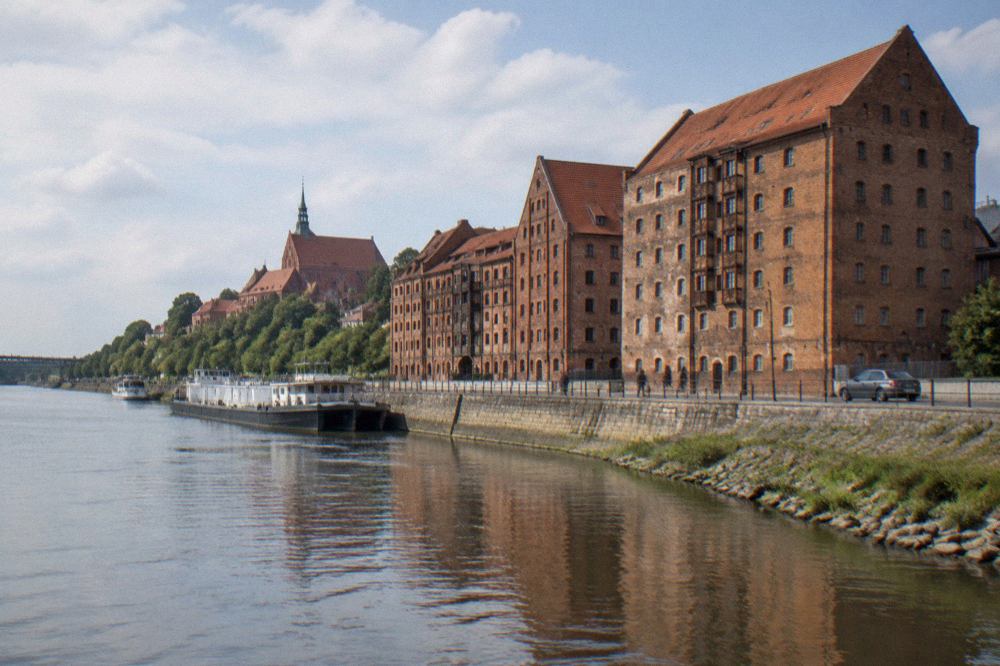 Rows of brick granary buildings rising above the Vistula riverbank in Grudziądz