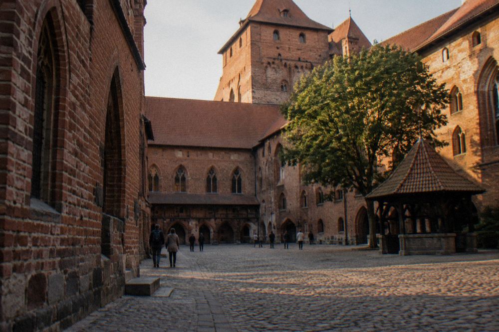 Courtyard inside Malbork Castle with high brick walls and arched windows