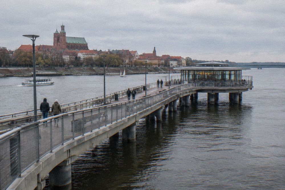 A long pier curving into the Vistula with a round glazed cafe at its end
