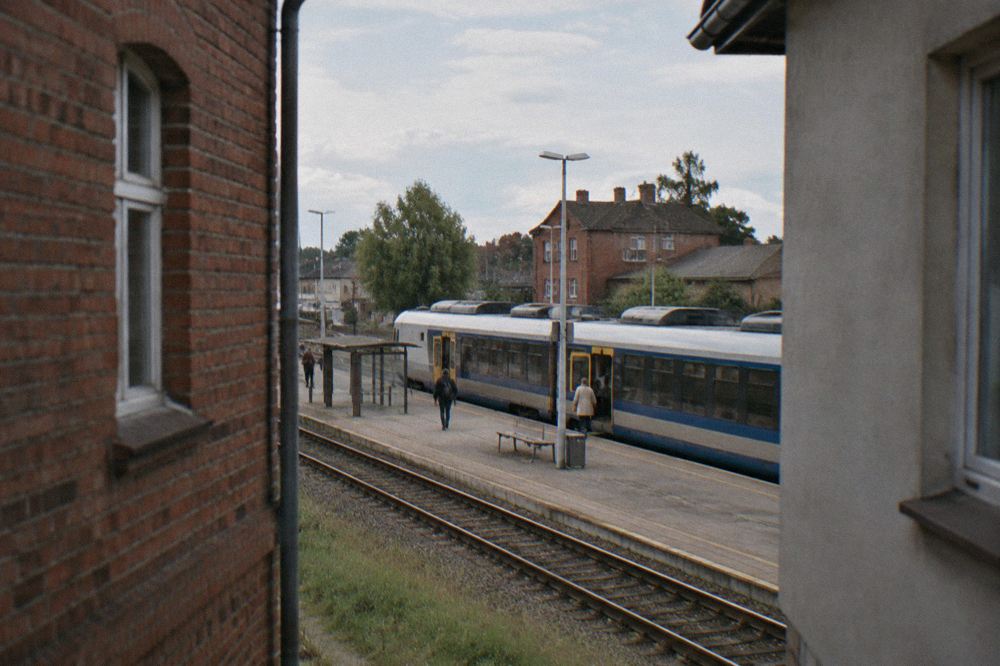 A small town railway station platform with a passenger train stopped alongside