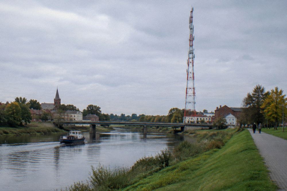 A tall radio transmission mast rising above flat open countryside