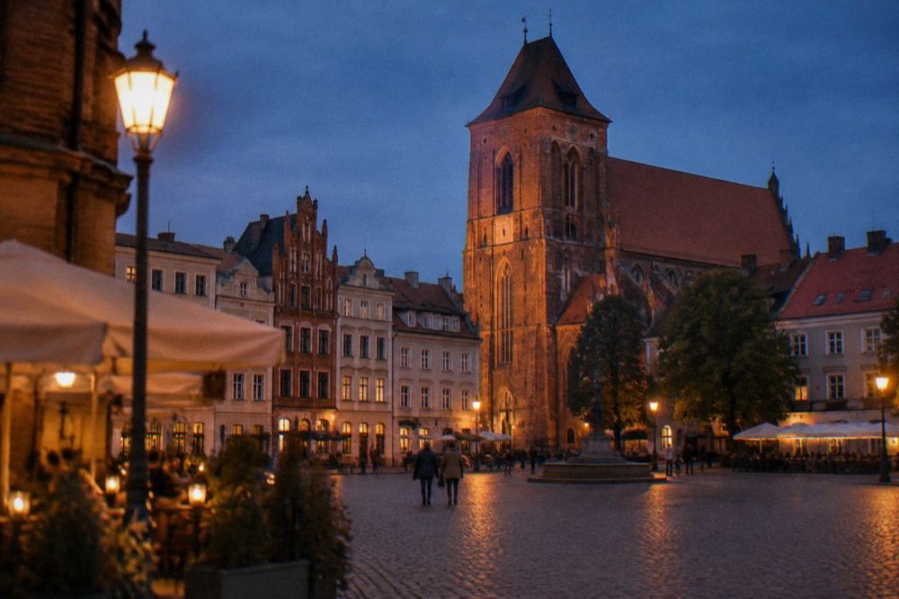 Gothic brick church towers above the rooftops of Toruń Old Town in evening light