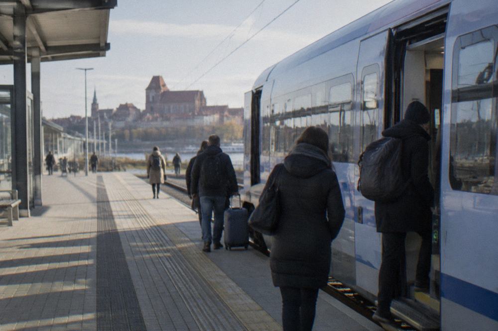 Passengers boarding a modern PKP Intercity train at a Polish railway station platform