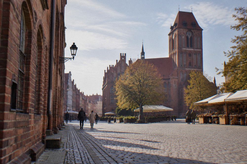Old town street with gothic brick buildings and a church tower in the background