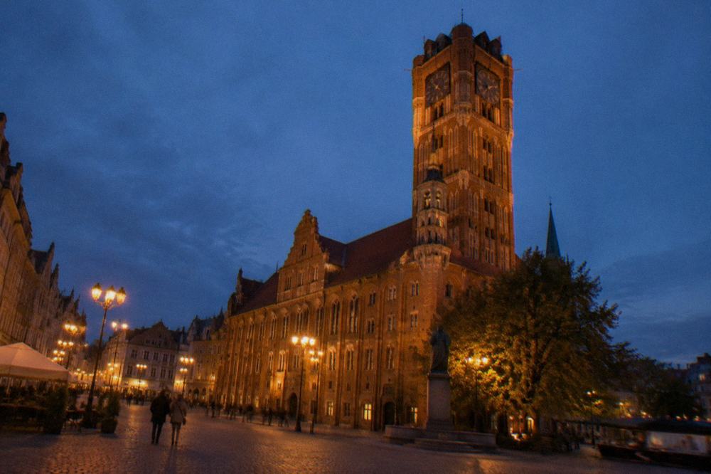Illuminated gothic town hall tower on a market square at dusk