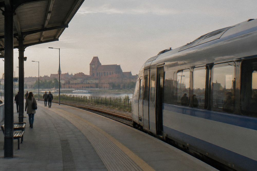 A modern intercity train standing at a platform beside a Polish railway station