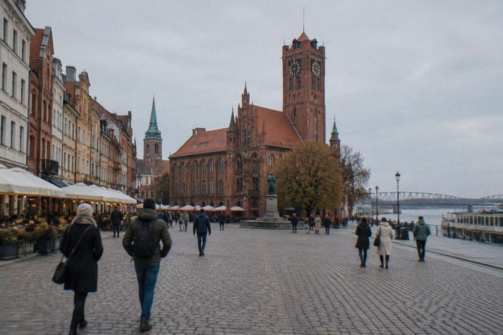 Visitors walking across the cobbled Rynek Staromiejski square in Toruń