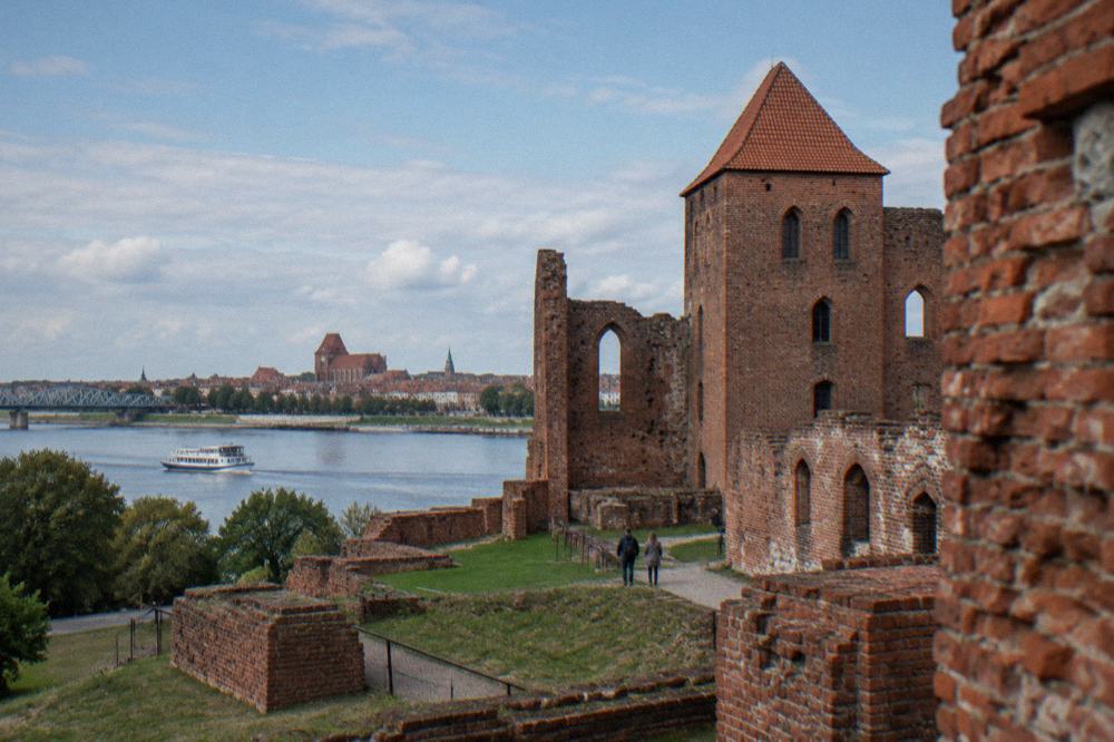 Red-brick ruins of the Teutonic Castle in Toruń under a blue sky