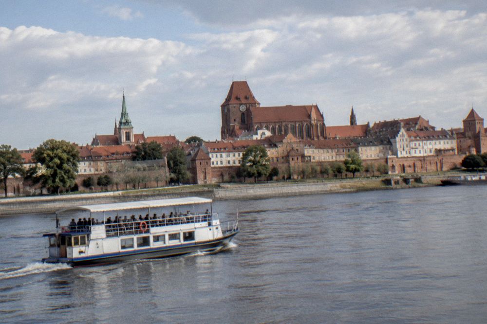 A boat on the Vistula river with the panorama of Toruń Old Town behind it