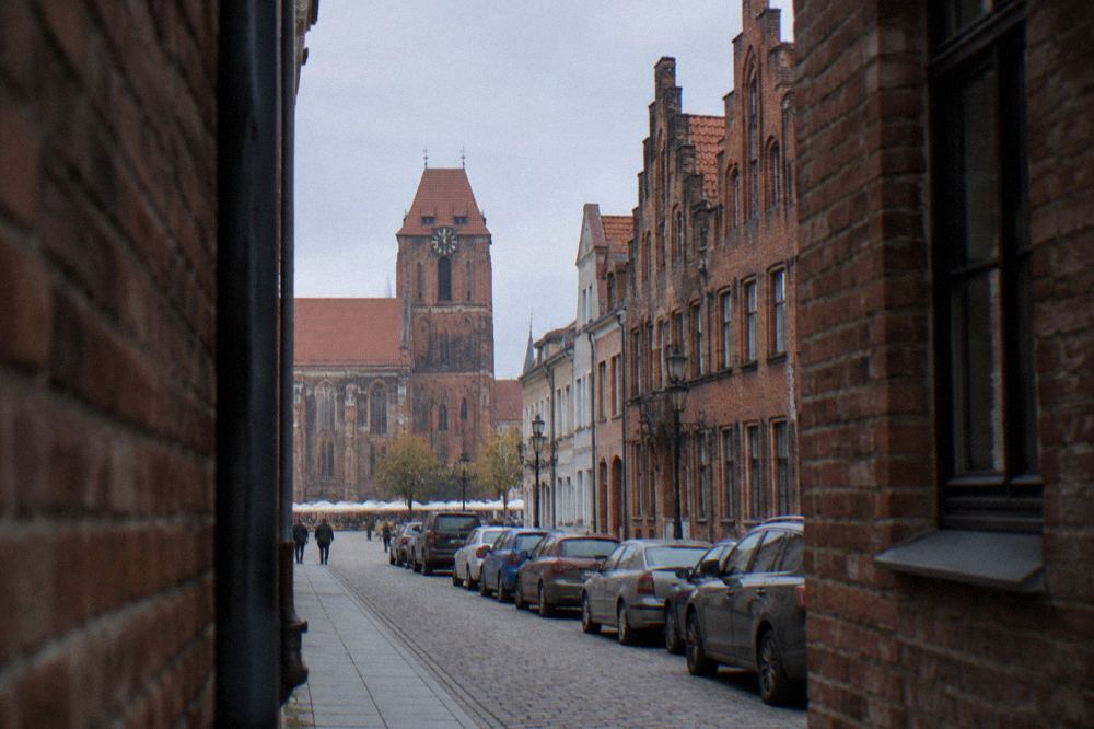 Cars parked along a street of brick buildings near Toruń's Old Town