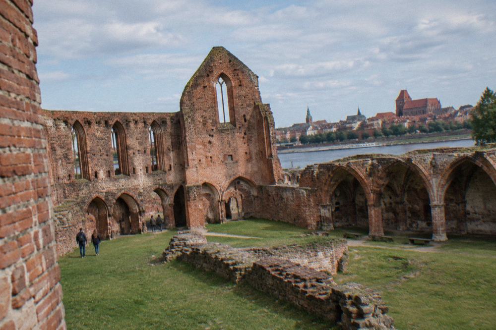 The ruins of the Teutonic Castle in Toruń with brick vaults and open grass inside