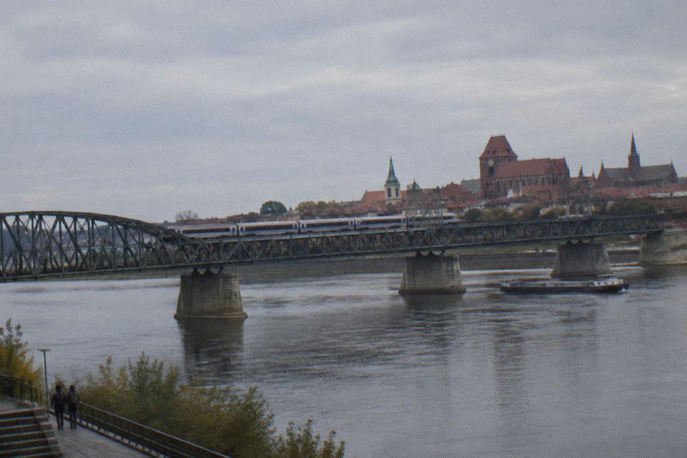 A long-distance train crossing a river bridge in northern Poland