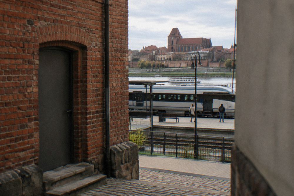 A railway platform sign reading Toruń Miasto under a clear sky