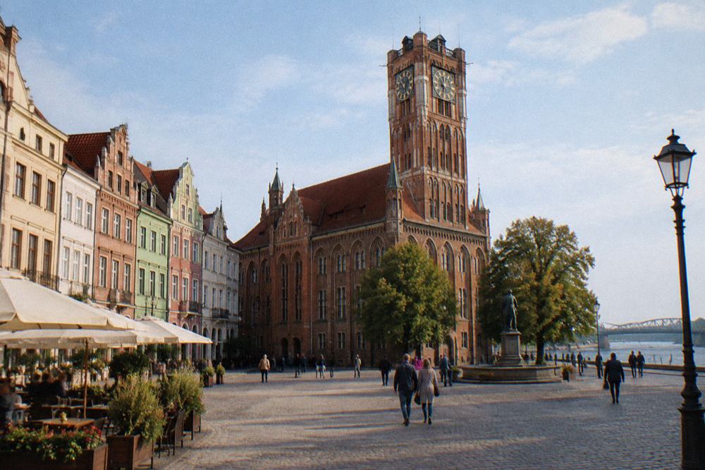 Colourful Gothic townhouses and the Old Town Hall tower on a market square in Toruń